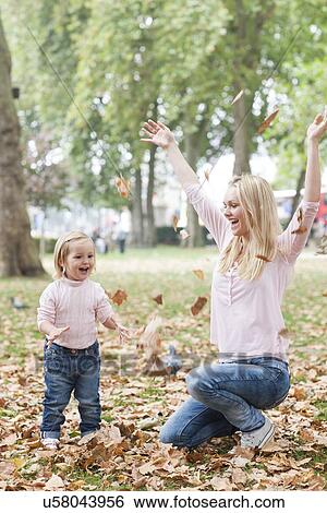Mother and daughter playing with leaves View Large Photo Image Stock Photograph - Mother and daughter playing with leaves. Fotosearch