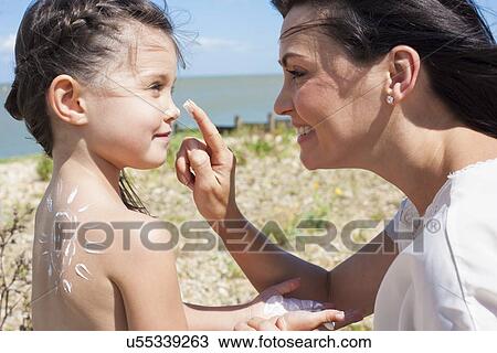 Stock Image - Mother applying suncream to daughter. Fotosearch