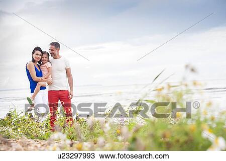 Stock Image - Parents on beach with daughter. Fotosearch