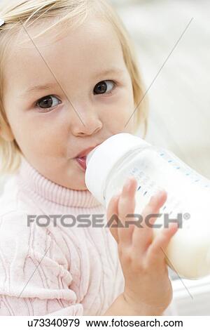 Stock Photo - Toddler holding a bottle of milk. Fotosearch