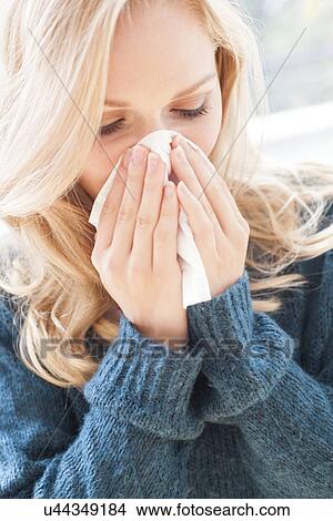 Picture - Woman blowing nose with tissue. Fotosearch