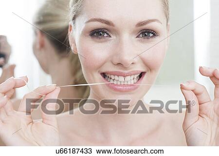 Stock Image - Woman flossing her teeth. Fotosearch