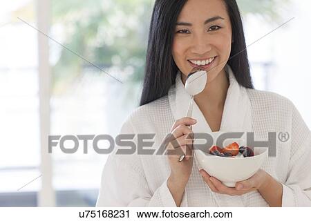 Stock Image - Woman holding bowl of fruit. Fotosearch