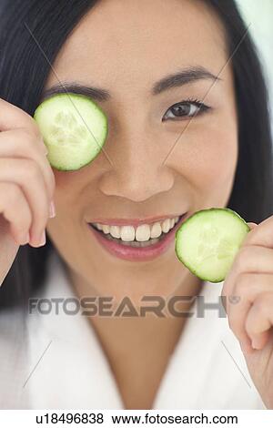 Stock Photo - Woman holding cucumber slices. Fotosearch