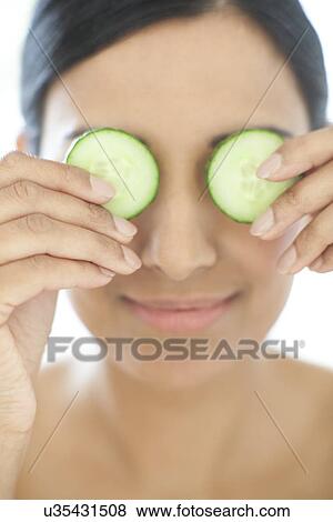 Stock Photo - Woman holding slices of cucumber. Fotosearch