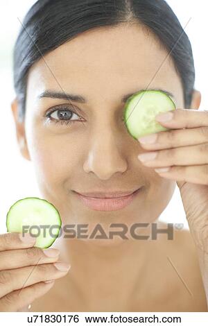 Stock Photograph - Woman holding slices of cucumber. Fotosearch