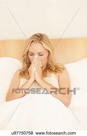 Woman in bed blowing nose on tissue View Large Photo Image Stock Photo - Woman in bed blowing nose on tissue. Fotosearch