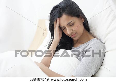 Woman in bed touching her head View Large Photo Image Stock Photo - Woman in bed touching her head. Fotosearch