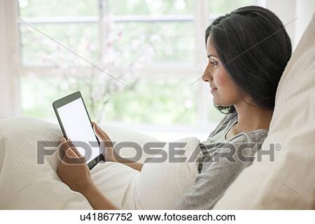 Woman in bed using digital tablet View Large Photo Image Stock Image - Woman in bed using digital tablet. Fotosearch