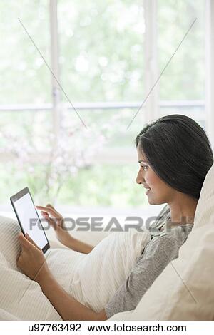 Woman in bed using digital tablet View Large Photo Image Stock Image - Woman in bed using digital tablet. Fotosearch