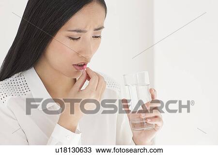 Stock Image - Woman taking painkiller. Fotosearch