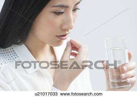 Stock Image - Woman taking painkiller. Fotosearch