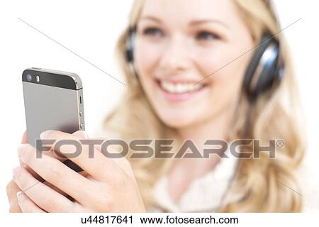 Woman wearing headphones holding smartpho View Large Photo Image Stock Image - Woman wearing headphones holding smartpho. Fotosearch