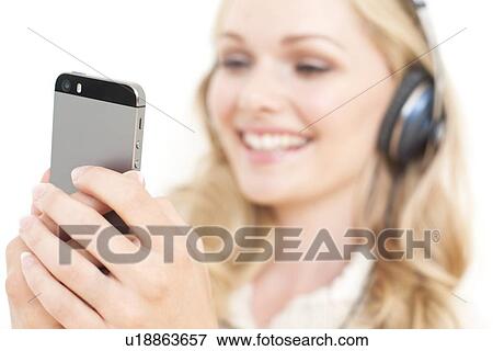 Stock Photo - Woman wearing headphones holding smartpho. Fotosearch