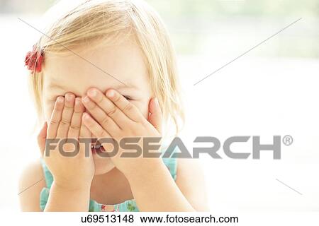 Stock Photo - Young girl covering face with hands. Fotosearch