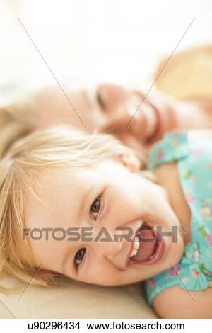 Picture - Young girl lying down laughing. Fotosearch