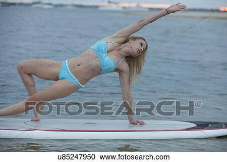 Young woman stretching on surfboard View Large Photo Image Stock Image - Young woman stretching on surfboard. Fotosearch