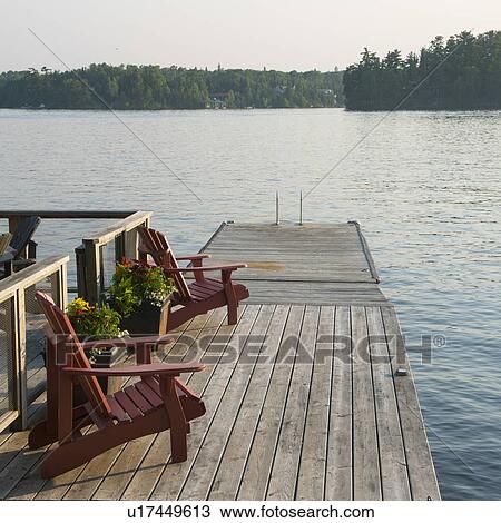 Adirondack chairs on a dock at the lakeside, Lake of The Woods, Ontario, Canada View Large Photo Image Stock Image - Adirondack chairs on a dock at the lakeside, Lake of The Woods, Ontario, Canada. Fotosearch