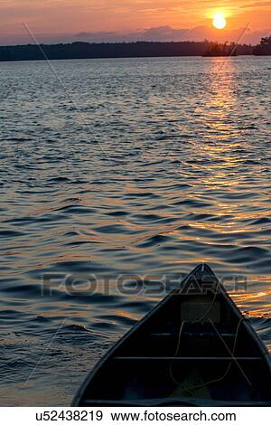 Stock Photo - Boat in a lake at sunset, Lake of The Woods, Ontario, Canada. Fotosearch