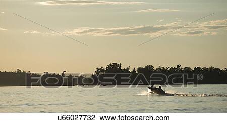 Stock Image - Boat moving in a lake, Lake of The Woods, Ontario, Canada. Fotosearch