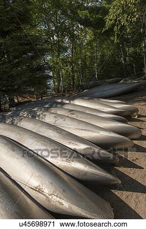 Stock Image - Bottoms of canoe boats lined up on the shoreline, Lake of The Woods, Ontario, Canada. Fotosearch