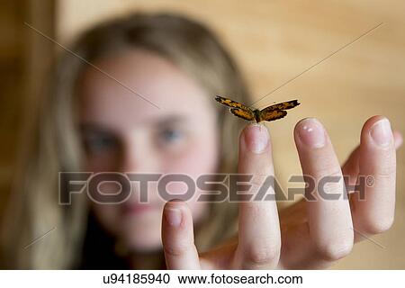 Stock Image - Butterfly perching on fingertip of a girl, Lake of The Woods, Ontario, Canada. Fotosearch