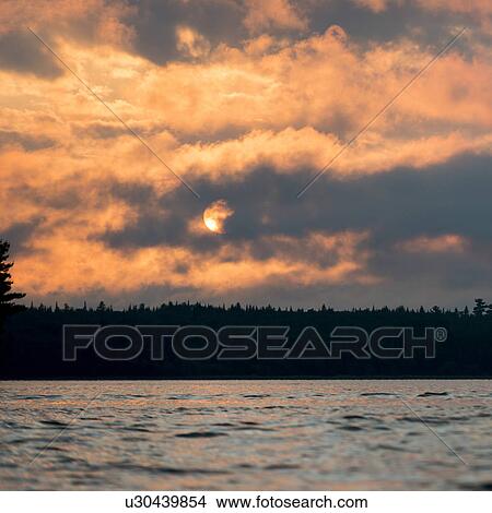Clouds eith sunglow over a lake at dusk, Lake of The Woods, Ontario, Canada View Large Photo Image Picture - Clouds eith sunglow over a lake at dusk, Lake of The Woods, Ontario, Canada. Fotosearch