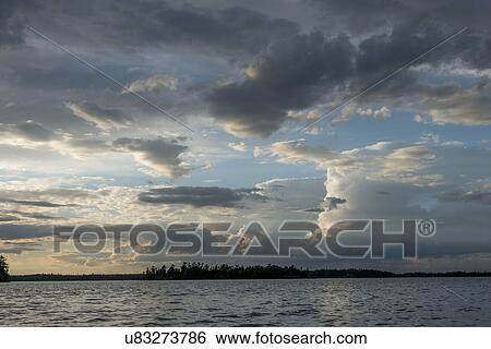 Stock Photograph - Clouds over a lake, Lake of The Woods, Ontario, Canada. Fotosearch