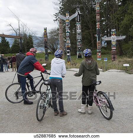 Cyclists viewing totem poles at Stanley Park, Vancouver, British Columbia, Canada View Large Photo Image Stock Photography - Cyclists viewing totem poles at Stanley Park, Vancouver, British Columbia, Canada. Fotosearch