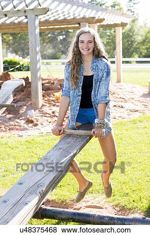 Stock Photo - Girl playing on a seesaw, Avonlea, Prince Edward Island, Canada. Fotosearch