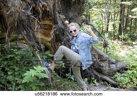 Stock Photograph - Girl pushing tree stump by foot, Lake of The Woods, Kenora, Lake of The Woods, Ontario, Canada. Fotosearch