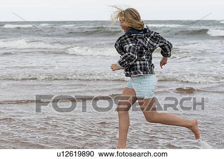 Stock Image - Girl running on the beach, Prince Edward Island, Canada. Fotosearch