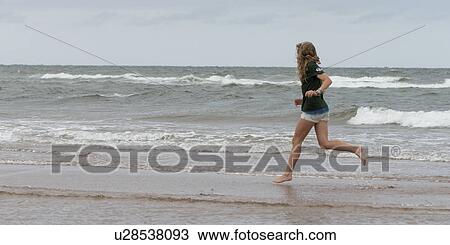Stock Image - Girl running on the beach, Prince Edward Island, Canada. Fotosearch