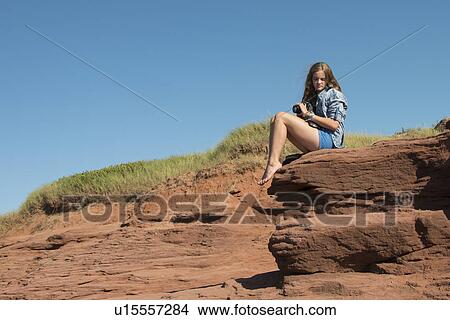 Picture - Girl sitting on rock, Cavendish Beach, Green Gables, Prince Edward Island, Canada. Fotosearch