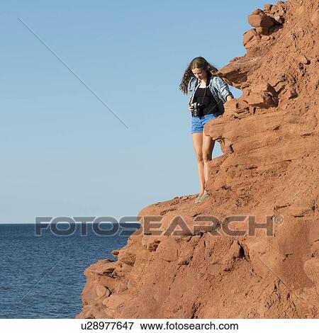 Stock Photo - Girl standing on cliff overlooking Atlantic Ocean, Green Gables, Cavendish, Prince Edward Island, Canada. Fotosearch