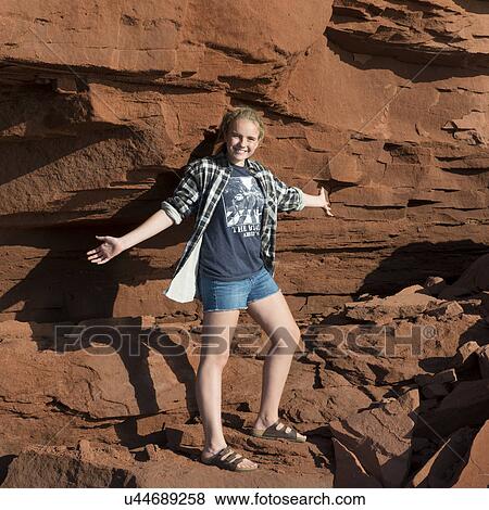 Stock Photo - Girl standing on cliff with arm outstretched, Green Gables, Cavendish, Prince Edward Island, Canada. Fotosearch