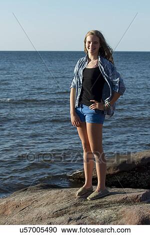 Stock Image - Girl standing on rock overlooking Atlantic Ocean, Cavendish Beach, Green Gables, Prince Edward Island, Canada. Fotosearch