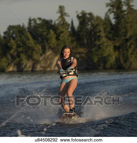 Stock Image - Girl waterskiing in a lake, Lake of The Woods, Ontario, Canada. Fotosearch