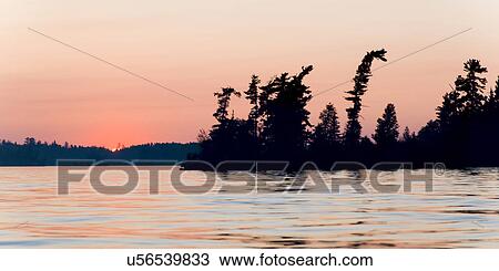 Stock Image - Glow of the sunset at dusk, Lake of The Woods, Ontario, Canada. Fotosearch