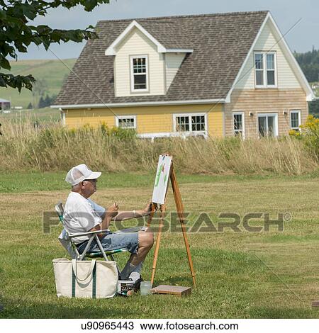 Stock Image - Man painting on canvas, Victoria, Prince Edward Island, Canada. Fotosearch