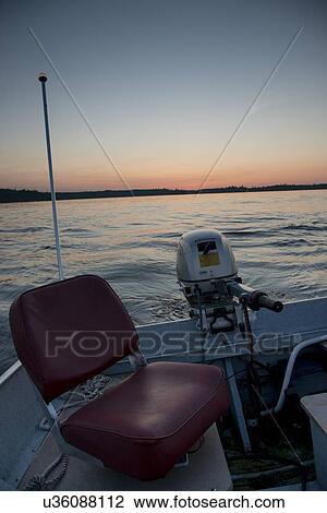 Stock Image - Motorboat in a lake at sunset, Lake of The Woods, Ontario, Canada. Fotosearch
