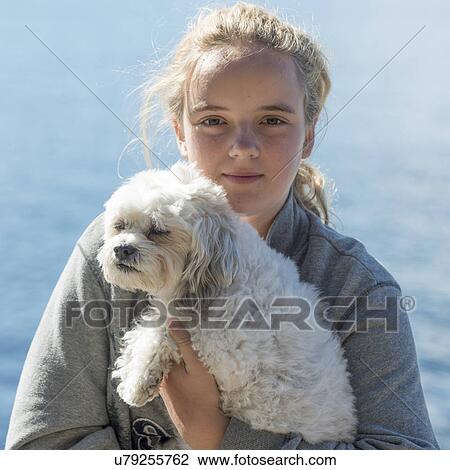 Stock Image - Portrait of a girl holding cute puppy, Lake of The Woods, Ontario, Canada. Fotosearch