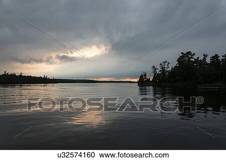 Stock Image - Silhouette of trees at dusk, Lake of The Woods, Ontario, Canada. Fotosearch