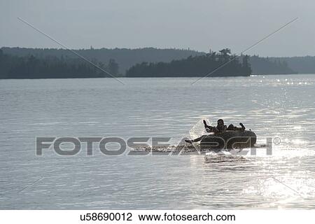 Stock Image - Tourists enjoying on inflatable raft in a lake, Lake of The Woods, Ontario, Canada. Fotosearch