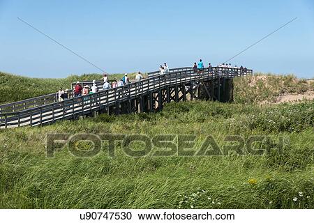 Stock Image - Tourists on wooden bridge at Cavendish Beach, Green Gables, Prince Edward Island, Canada. Fotosearch