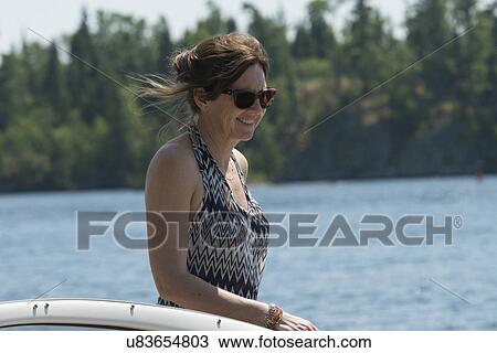 Stock Image - Woman standing on a boat, Lake of The Woods, Ontario, Canada. Fotosearch