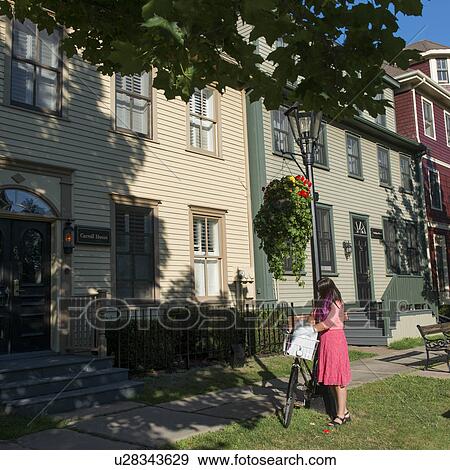 Stock Photo - Woman with a bicycle in front of houses, Charlottetown, Prince Edward Island, Canada. Fotosearch