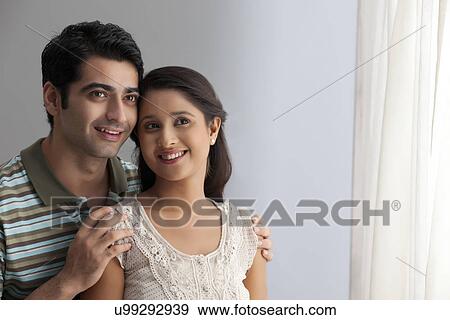 Stock Photo - Affectionate young couple smiling while standing together . Fotosearch