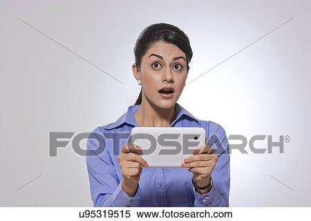 Amazed businesswoman holding digital tablet over gray background View Large Photo Image Stock Photography - Amazed businesswoman holding digital tablet over gray background. Fotosearch