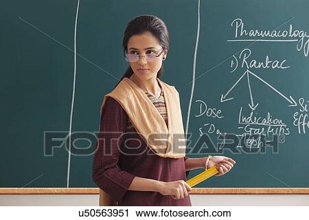 An angry female lecturer holding ruler against green board View Large Photo Image Stock Image - An angry female lecturer holding ruler against green board . Fotosearch